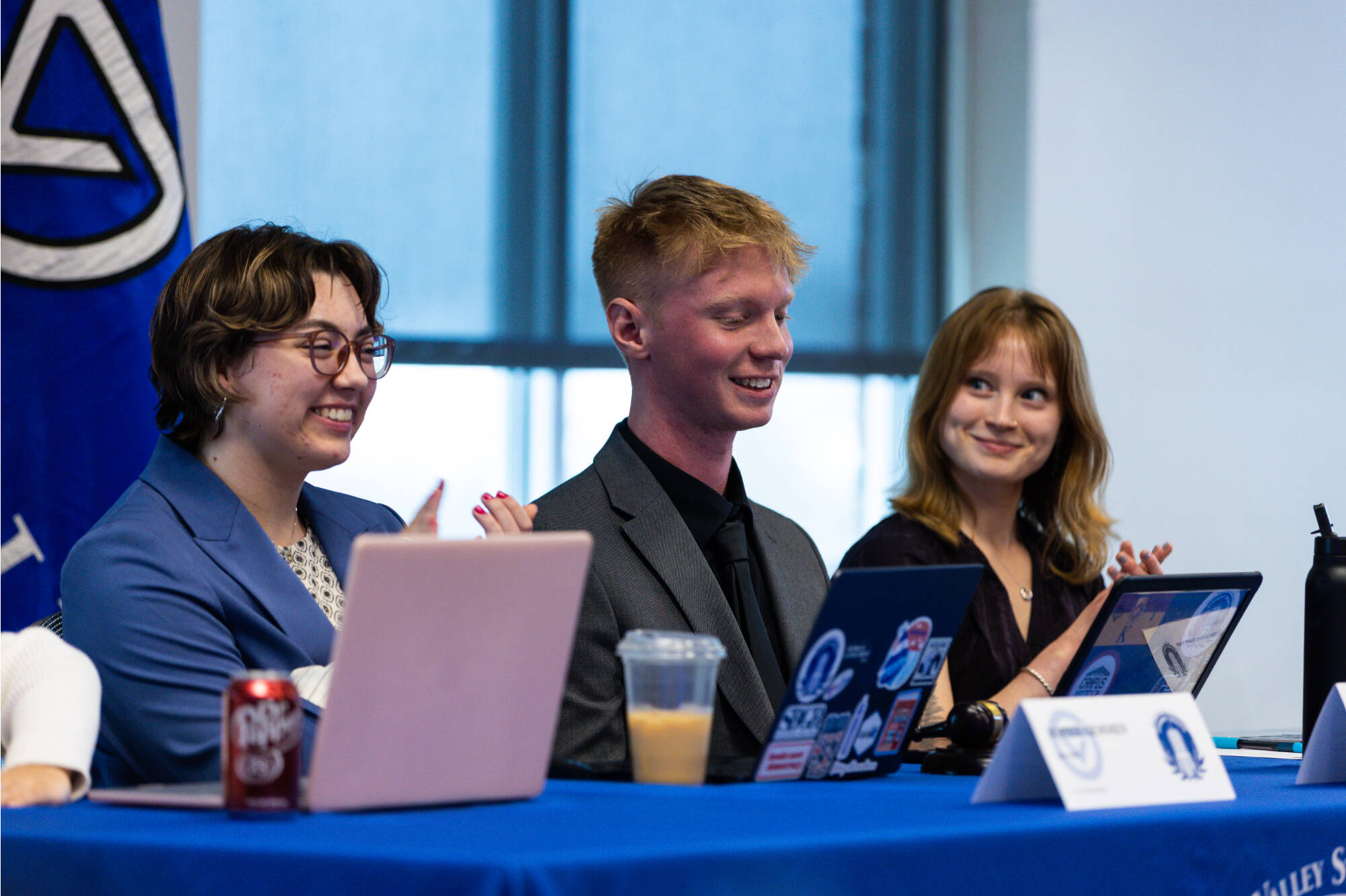 Three Student Senate leaders smiling during a meeting.